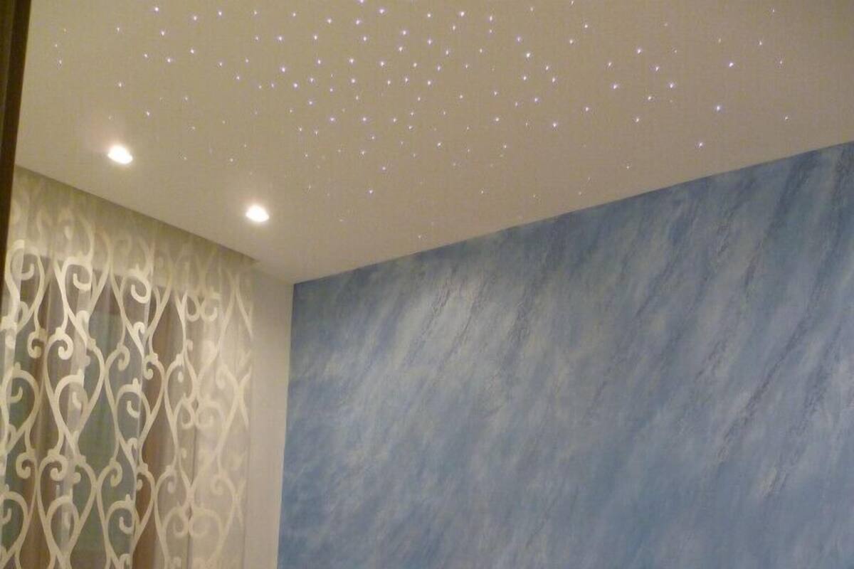 Een slaapkamer met een bed, nachtkastje en decoratief wandpaneel.