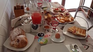 Een ontbijttafel met diverse gerechten, een fruitschaal, een karnmelk pitcher en een raam met uitzicht.