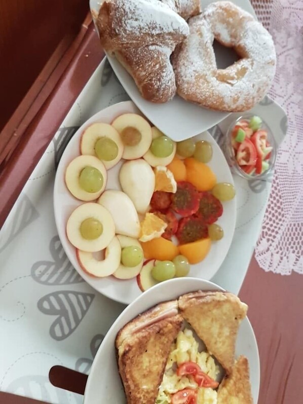 A breakfast tray with sliced apples, grapes, orange segments, and a small salad.