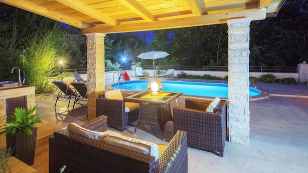 An outdoor patio with wicker furniture, a pool, and a stone pillar. - Holiday home with pool and garden (Vodnjan)