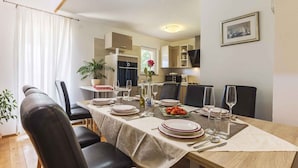 A dining area with a table set for four, chairs, a potted plant, and a view into the kitchen. - Holiday home with pool and garden (Vodnjan)