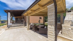 A covered outdoor patio with stone columns, a stone fireplace, and outdoor furniture. - Holiday home with pool and garden (Vodnjan)