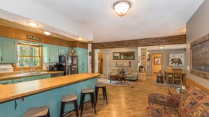 A kitchen with a bar area, wooden flooring, and a sofa in the living area.