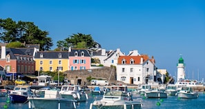 A harbor with colorful buildings, a lighthouse, and boats docked. - Homerez - House in Sauzon (Sauzon)