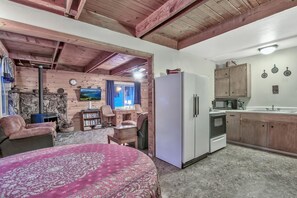 Ein gemütliches Zimmer mit Bett, Schreibtisch, Kamin und Küchenzeile.