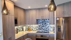 A modern kitchen with wooden cabinets, stainless steel appliances, a double sink, and pendant lighting. - On Dover Beach, close to golf, surfing and much more. Discounts available (St-Lawrence Gap)