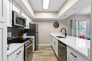 Una cocina moderna con armarios blancos, electrodomésticos de acero inoxidable y piso de madera.