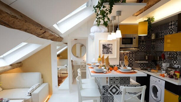 A modern kitchen with a dining area, featuring a skylight, a washing machine, and patterned tiles.