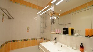 A bathroom with a bathtub, a shower, a sink with toiletries, and a mirror.