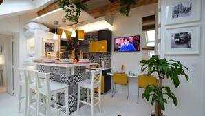 A modern kitchen with a central island, white bar stools, and a dining table.