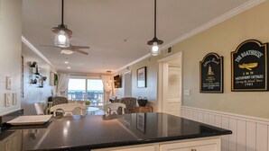 A spacious kitchen with a large island, pendant lights, and a view to a balcony. - Sea Master 105 - Two Bedroom, Two Bath Oceanview Condo (Murrells Inlet)