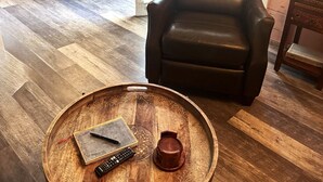 A cozy living room with a leather chair, a wooden coffee table, and a dining area with a table and chairs. - LAKEFRONT CABIN 1Bdrm/Deertrail2shore/Rowboat/SUP/FishinPole/Pet/30mins 2Durango (Bayfield)