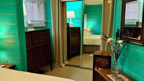 A room with a bed, a desk with a lamp, a mirror, and a window with blinds. - LAKEFRONT CABIN 1Bdrm/Deertrail2shore/Rowboat/SUP/FishinPole/Pet/30mins 2Durango (Bayfield)