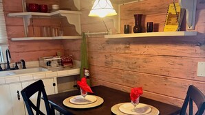 A dining area with a wooden table set for two, black chairs, and a hanging light fixture above. - LAKEFRONT CABIN 1Bdrm/Deertrail2shore/Rowboat/SUP/FishinPole/Pet/30mins 2Durango (Bayfield)