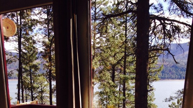A deck with a chair and a table, overlooking a lake and trees. - LAKEFRONT CABIN 1Bdrm/Deertrail2shore/Rowboat/SUP/FishinPole/Pet/30mins 2Durango (Bayfield)