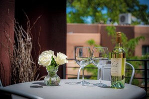 A table with a bottle of wine, two glasses, and a vase of white roses. - Eye Candy Loft | Modern Santa Fe Loft | Railyard District (Santa Fe)