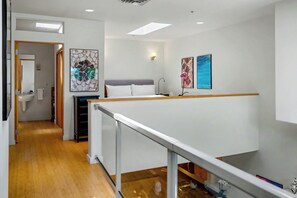 A hotel room with a bed, a desk, a chair, a window, and a bathroom. - Eye Candy Loft | Modern Santa Fe Loft | Railyard District (Santa Fe)
