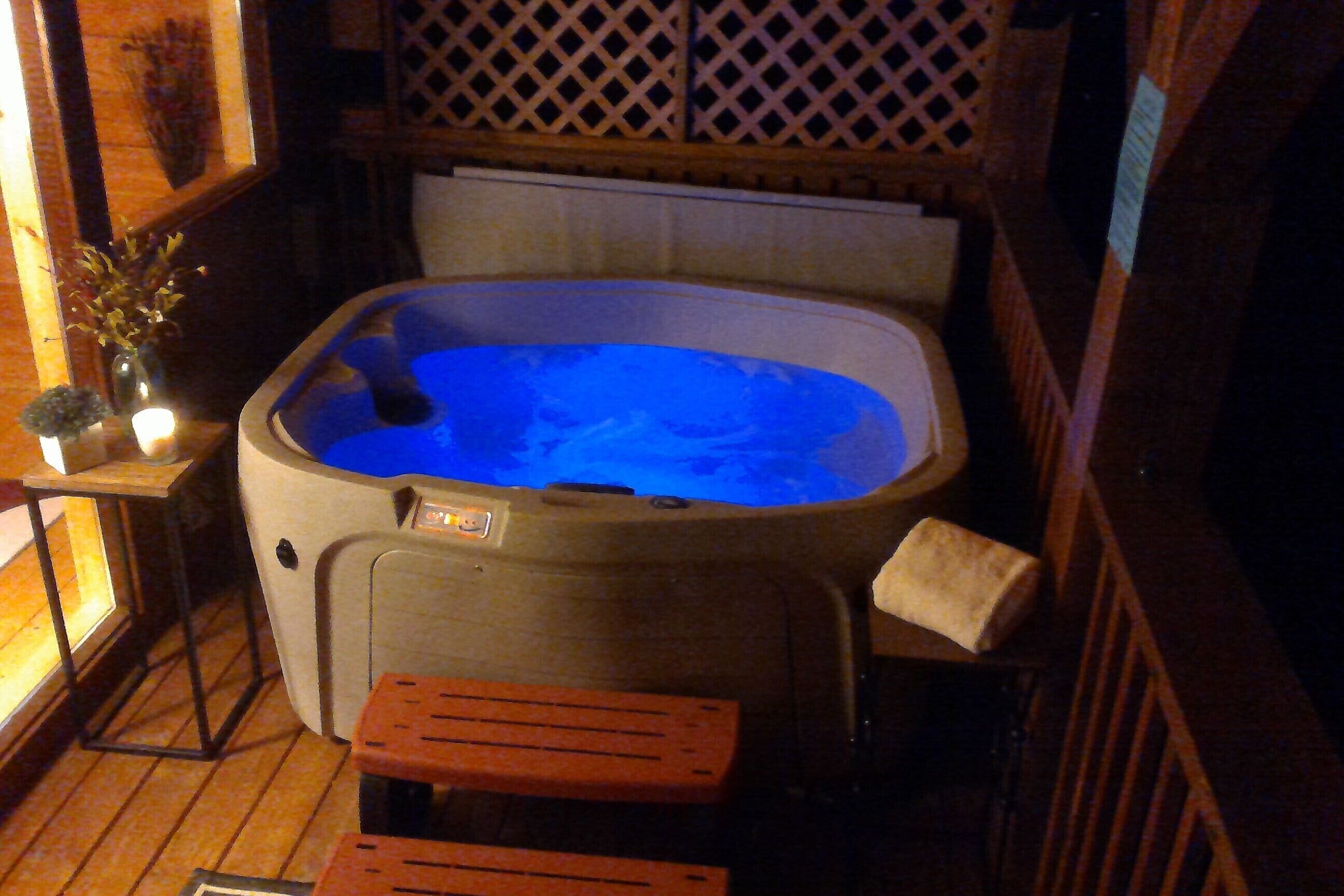 A hot tub with a wooden deck and a small table with a candle.