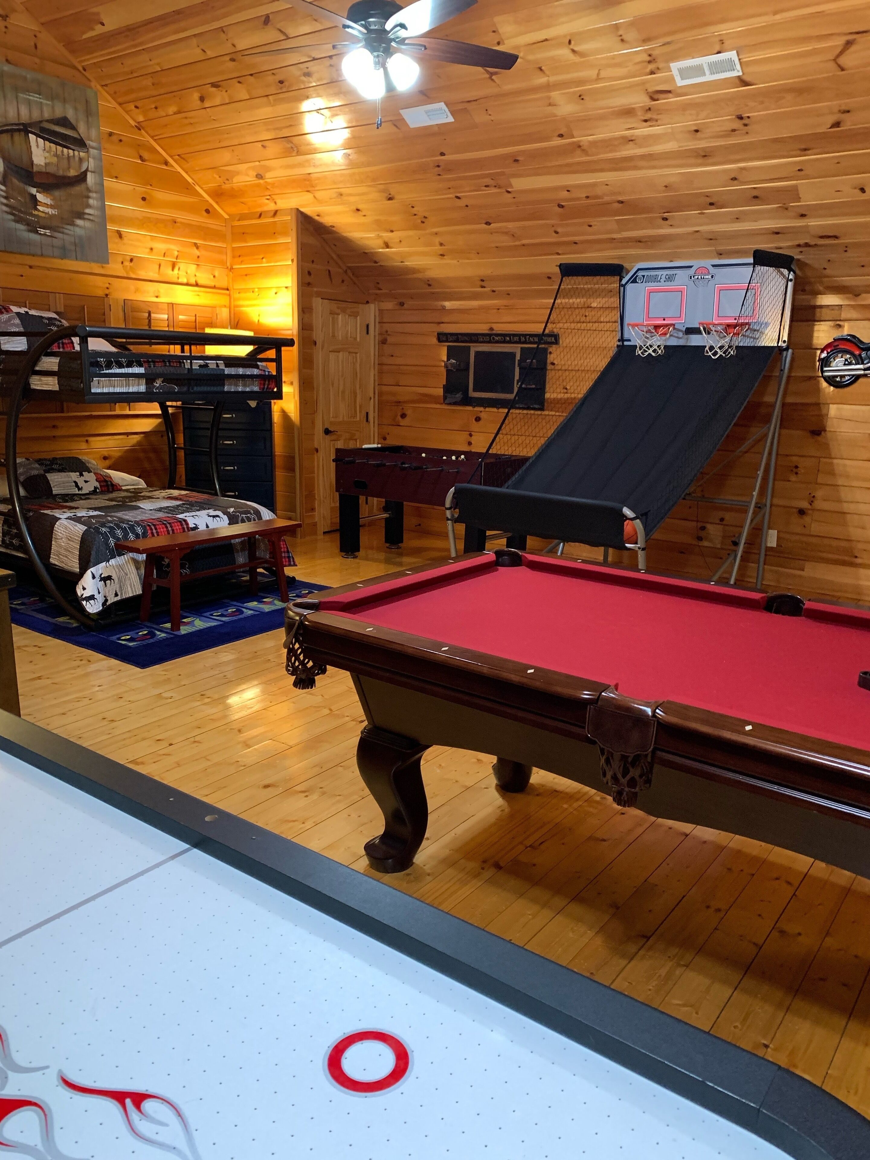 A pool table with a red felt surface, a pool cue, and a billiard ball rack.