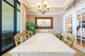 Un comedor con una mesa grande, sillas de madera, un candelabro y un espejo grande en la pared.