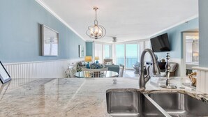 A modern kitchen with a marble countertop, stainless steel sink, and a chandelier. - One Ocean Place 1102 2 Bedrooms, 2 Bathrooms, Oceanfront (Garden City Beach)