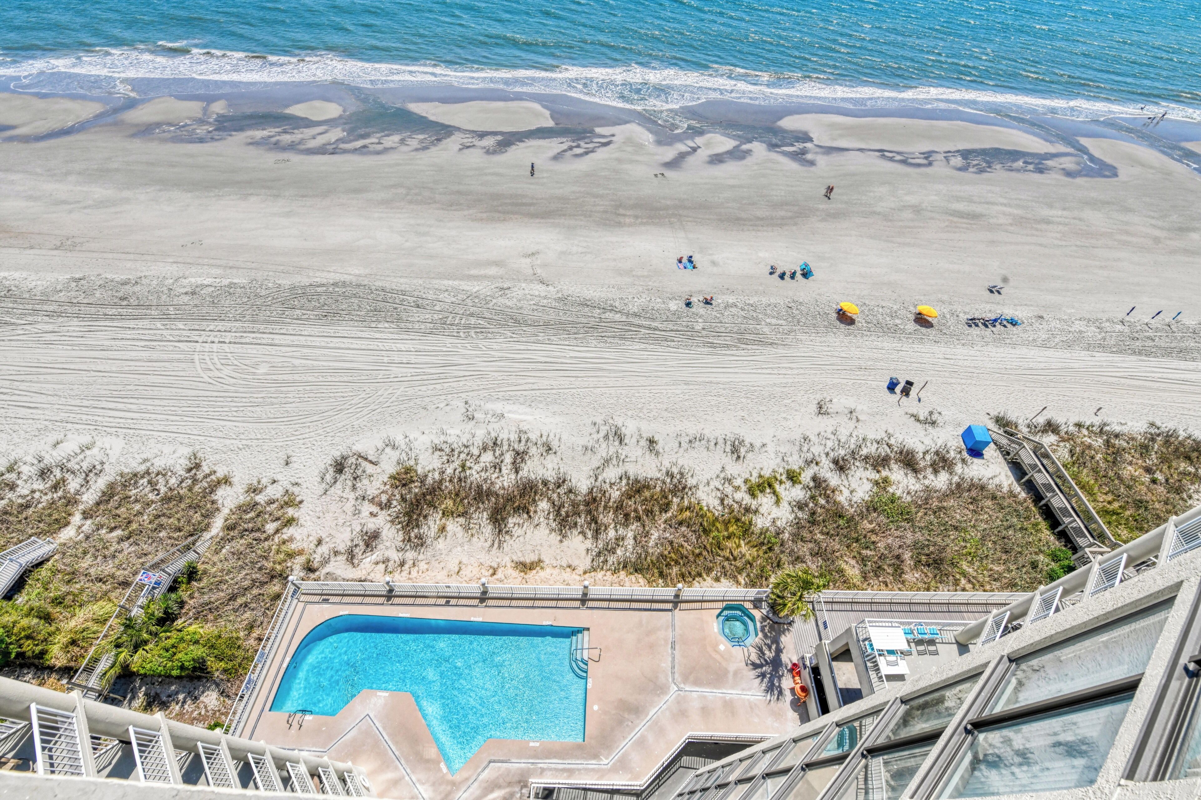 A pool area with a clear view of the beach and ocean.