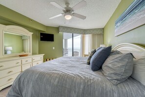 A bedroom with a bed, a dresser, a ceiling fan, and a view of the ocean. - One Ocean Place 201 - Spacious three-bedroom, three-bath oceanfront condo (Garden City Beach)
