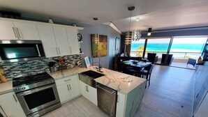 A modern kitchen with a large island, stainless steel appliances, and a view of the ocean.