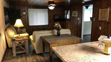 L’intérieur d’un chalet accueillant, avec un plafond en bois, un canapé blanc, une table basse en bois et une petite table avec une lampe.