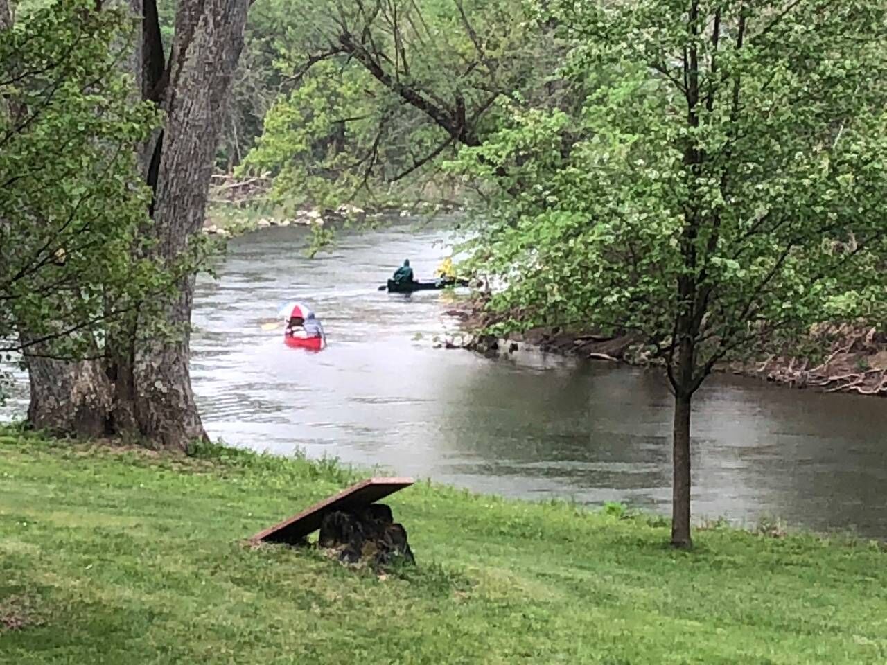 Une rivière où naviguent des bateaux, bordée d’arbres et de rives verdoyantes.