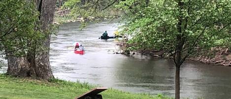 Une rivière où naviguent des bateaux, bordée d’arbres et de rives verdoyantes.