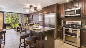 A modern kitchen with dark wood cabinets, stainless steel appliances, and a large island with bar stools.