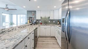 A modern kitchen with white cabinets, a stainless steel refrigerator, and a granite countertop. - Pure luxury in North Myrtle Beach (North Myrtle Beach)
