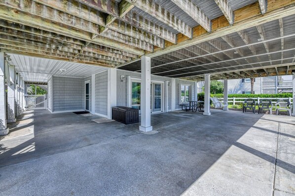 A covered outdoor area with a concrete floor, white columns, and a picnic table.