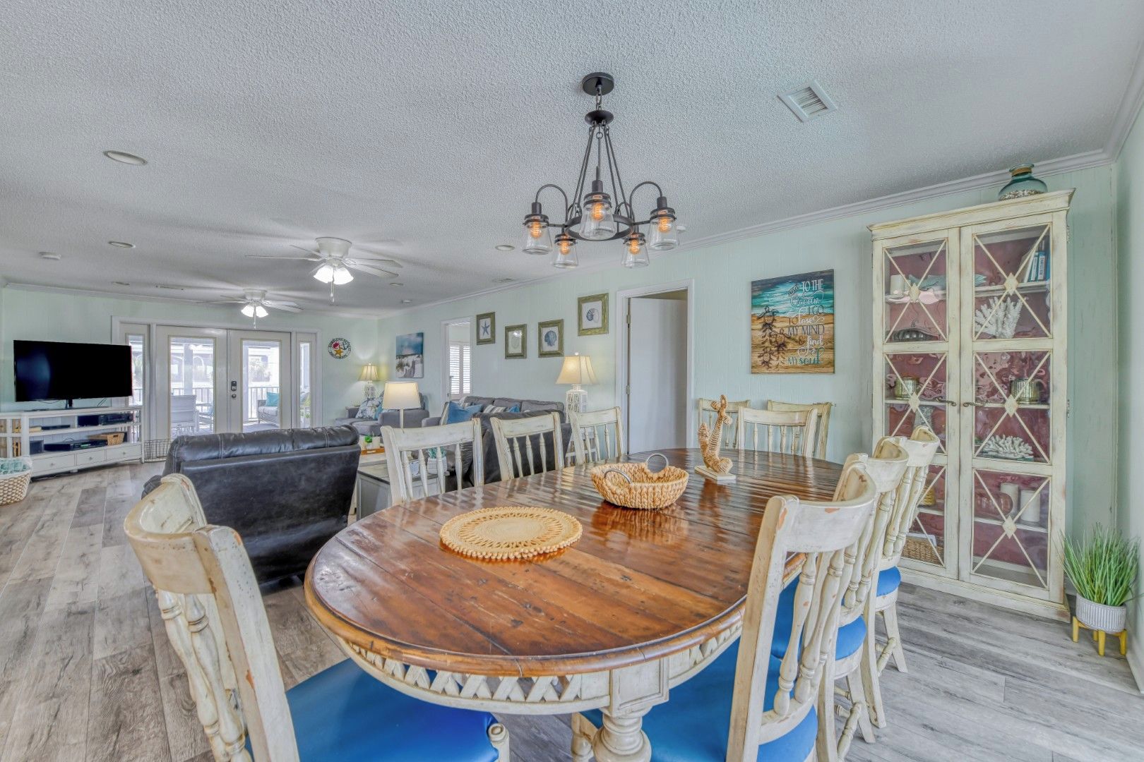 A spacious living room with a wooden dining table, comfortable seating, and a television.