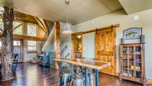 A dining area with a wooden table and chairs, a hanging light fixture, and a wooden cabinet with glass doors. - Boat Slip Included, Lake Views, Close to SDC! (Branson)