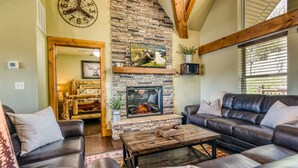 A cozy living room with a stone fireplace, leather sofas, and a wooden ceiling. - Boat Slip Included, Lake Views, Close to SDC! (Branson)
