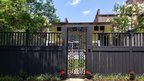 A gated entrance with a decorative gate, surrounded by potted plants and a clear sky. - The Cottage in the Historic South Main Arts District, Walk Everywhere Downtown (Memphis)