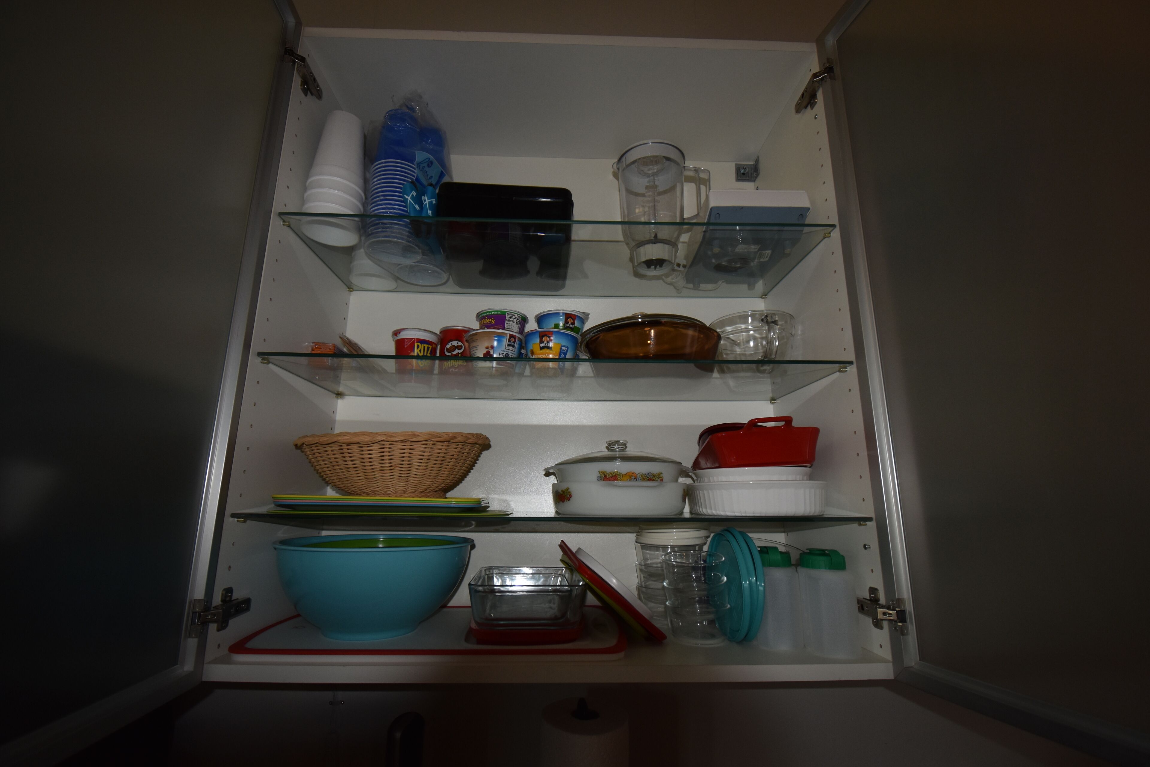 A kitchen pantry with shelves holding various kitchen items like bowls, jars, and containers.