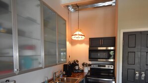 A kitchen with a wooden countertop, stainless steel appliances, and a black door. - The Cottage in the Historic South Main Arts District, Walk Everywhere Downtown (Memphis)