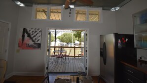 A kitchen with a refrigerator, a dining table with chairs, a ceiling fan, and a view through a window to an outdoor deck. - The Cottage in the Historic South Main Arts District, Walk Everywhere Downtown (Memphis)