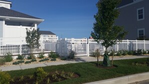Un barrio residencial con una cerca blanca, un árbol y un césped bien cuidado.
