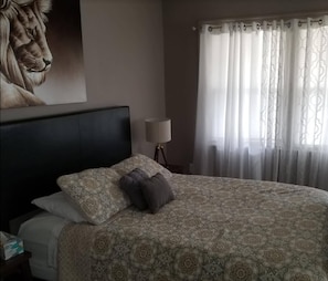 Relax in a cozy retreat with a large bed, a wall-mounted lamp, and a framed picture of a lion.