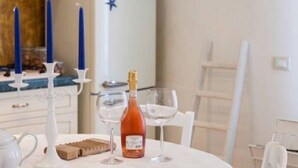 Une table à manger avec une bouteille de vin, deux verres à vin, une théière et un chandelier avec des bougies.