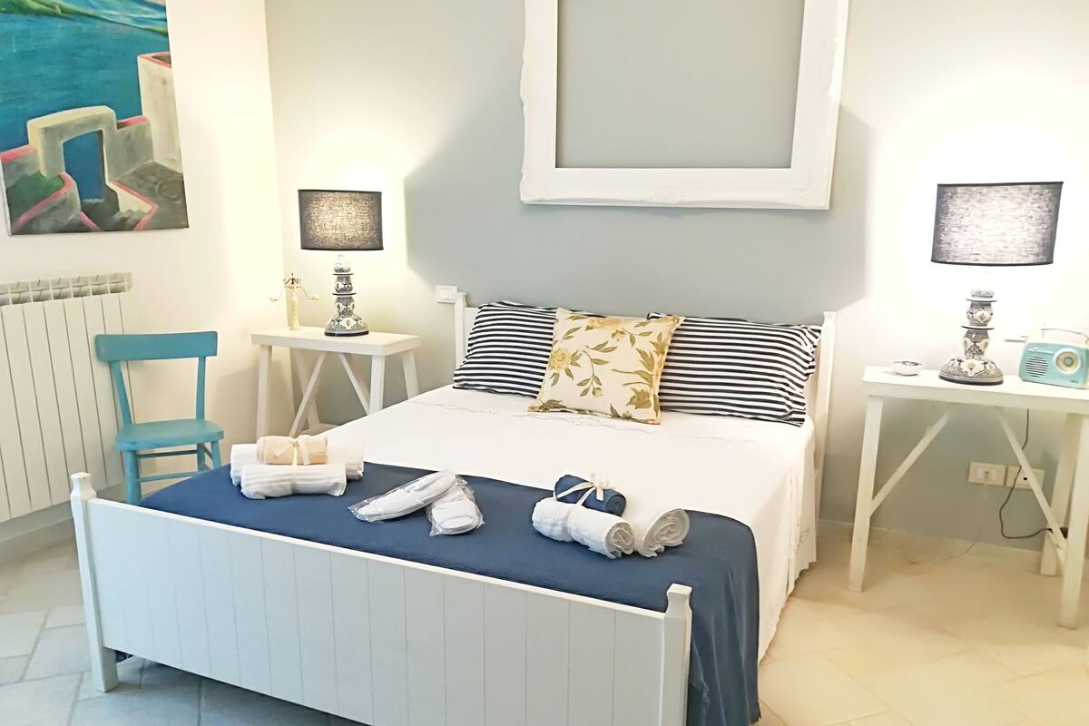 A neatly arranged bedroom with a bed, bedside tables, a chair, and a lamp.