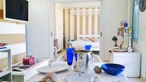 Une chambre d’hôtel équipée d’une table à manger pour deux personnes, d’un téléviseur et d’un lit avec une literie à rayures.