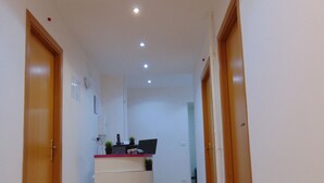 Un corridoio con una reception, due porte in legno e un pavimento piastrellato.