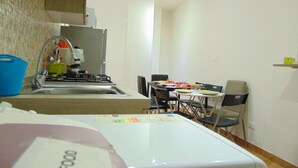 Una cucina compatta con lavello, fornello e zona pranzo con sedie e tavolo.
