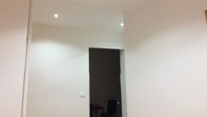 Una stanza con pareti bianche, una luce a soffitto e un ingresso che conduce in un'altra stanza.