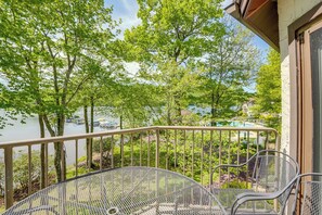 Un balcon avec une balustrade en métal, une table ronde en métal et deux chaises.